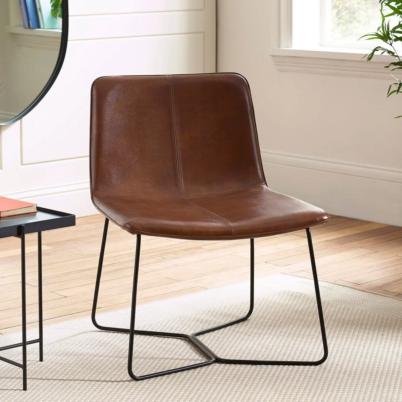 Brown leather accent chair with black metal legs on light rug in modern living room