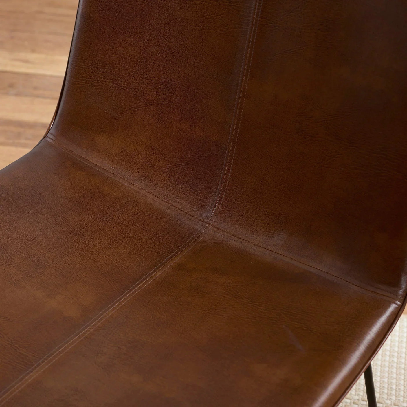 Closeup of brown faux leather dining chair seat with visible stitching detail