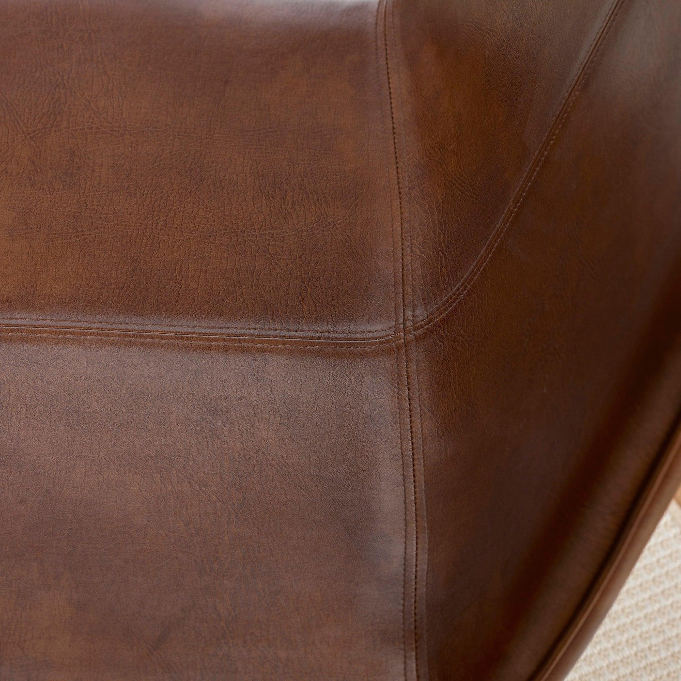 Closeup view of brown leather sofa upholstery with detailed stitching