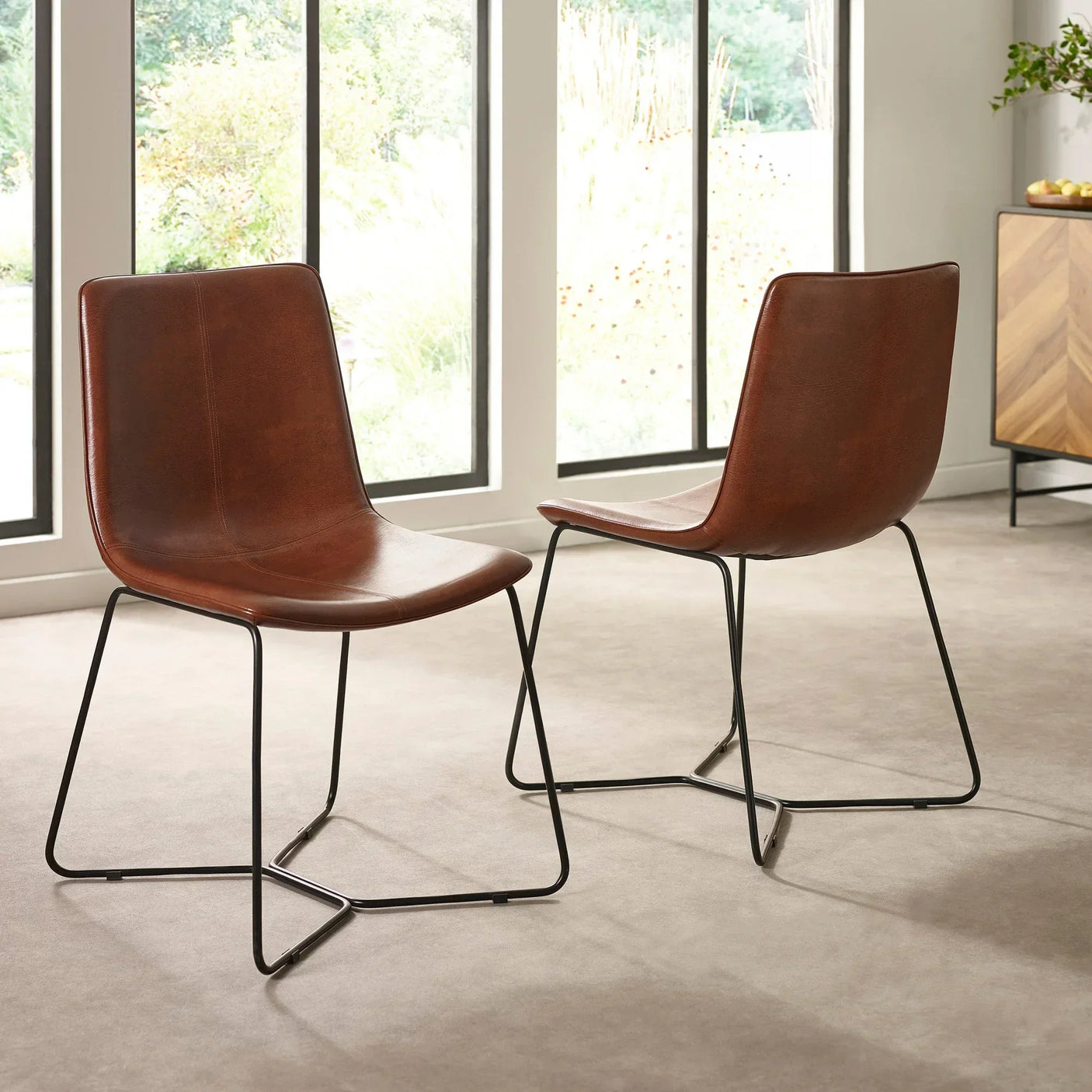 Pair of brown leather dining chairs with metal legs in modern dining room