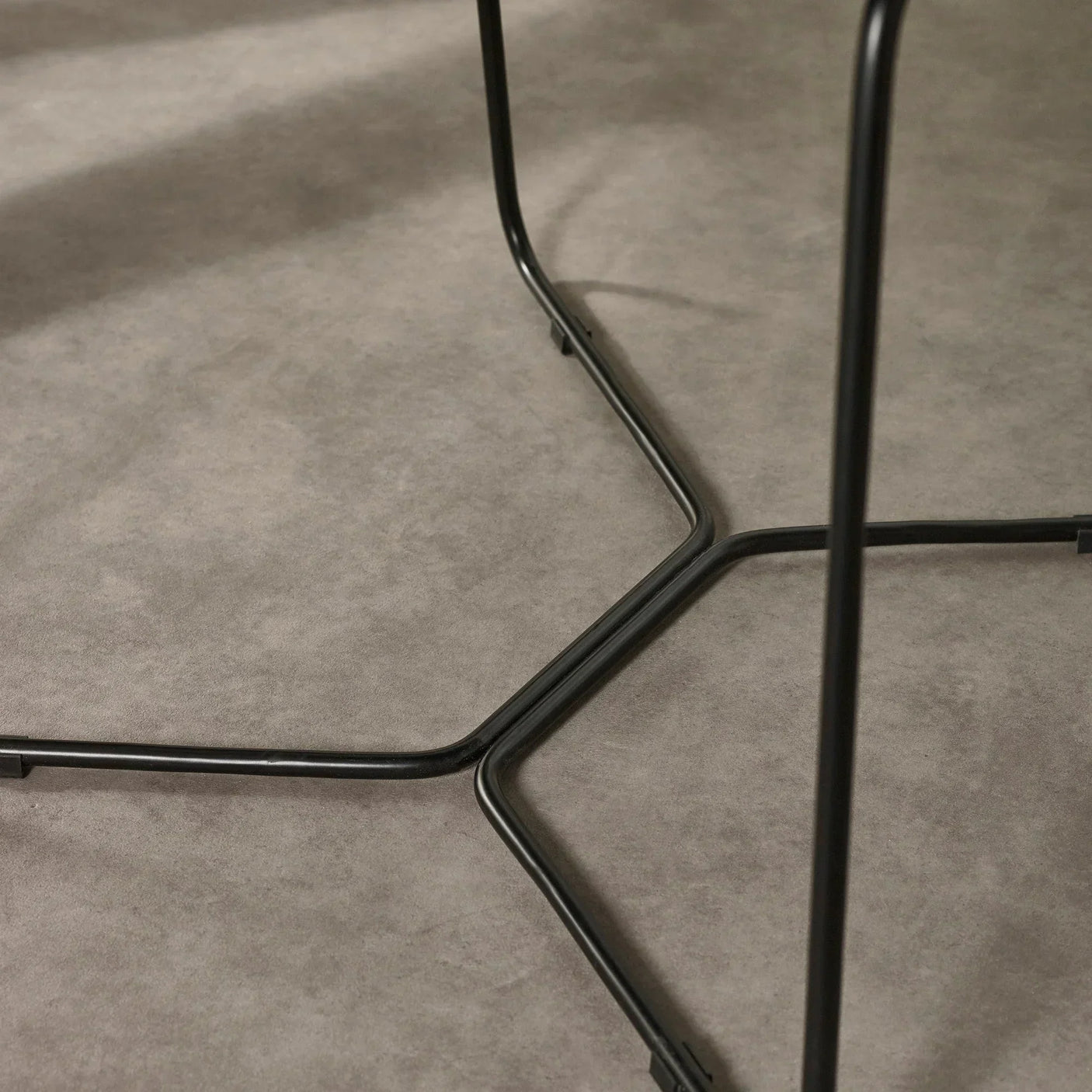 Black metal table legs with modern cross design on grey floor