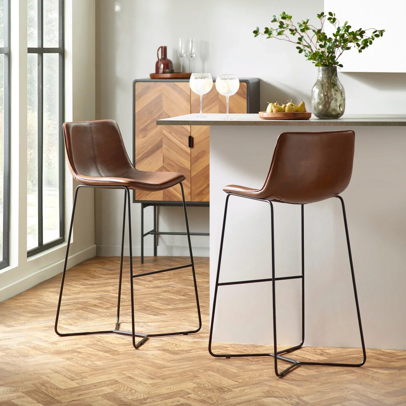 Brown leather bar stools with black metal legs at modern kitchen breakfast bar