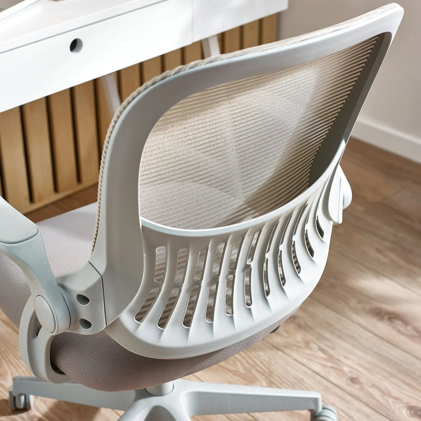 Mesh office chair with ergonomic backrest and light grey frame on wood floor
