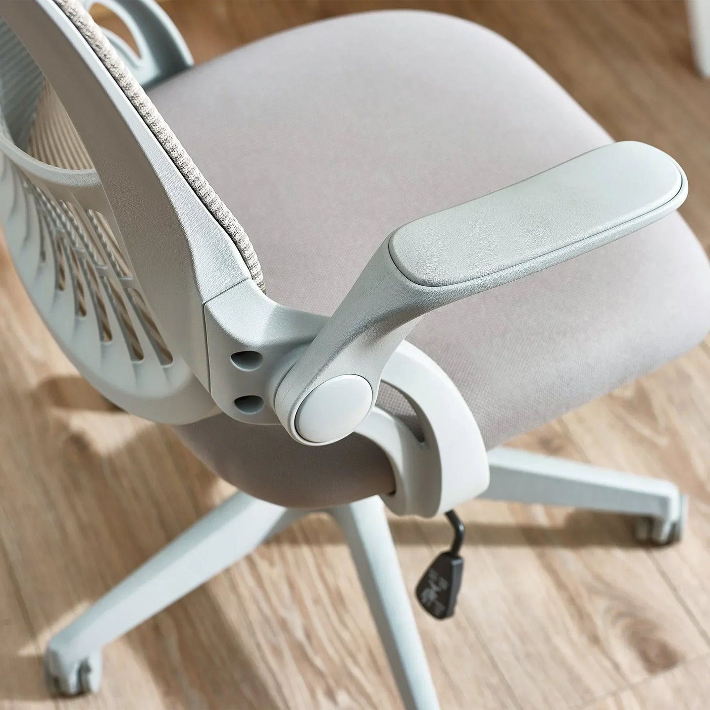 Light grey office chair with mesh backrest and padded seat on wooden floor