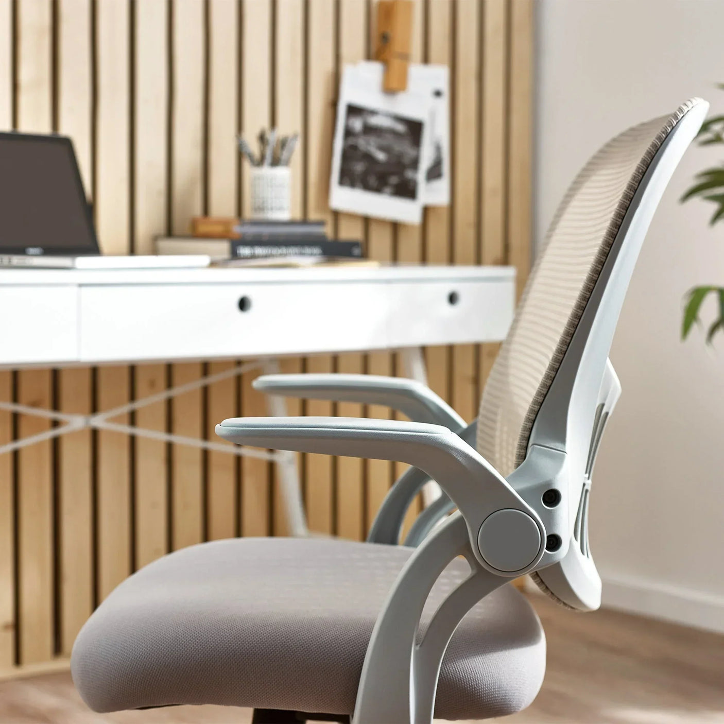 Grey mesh office chair with ergonomic backrest and armrest beside white desk