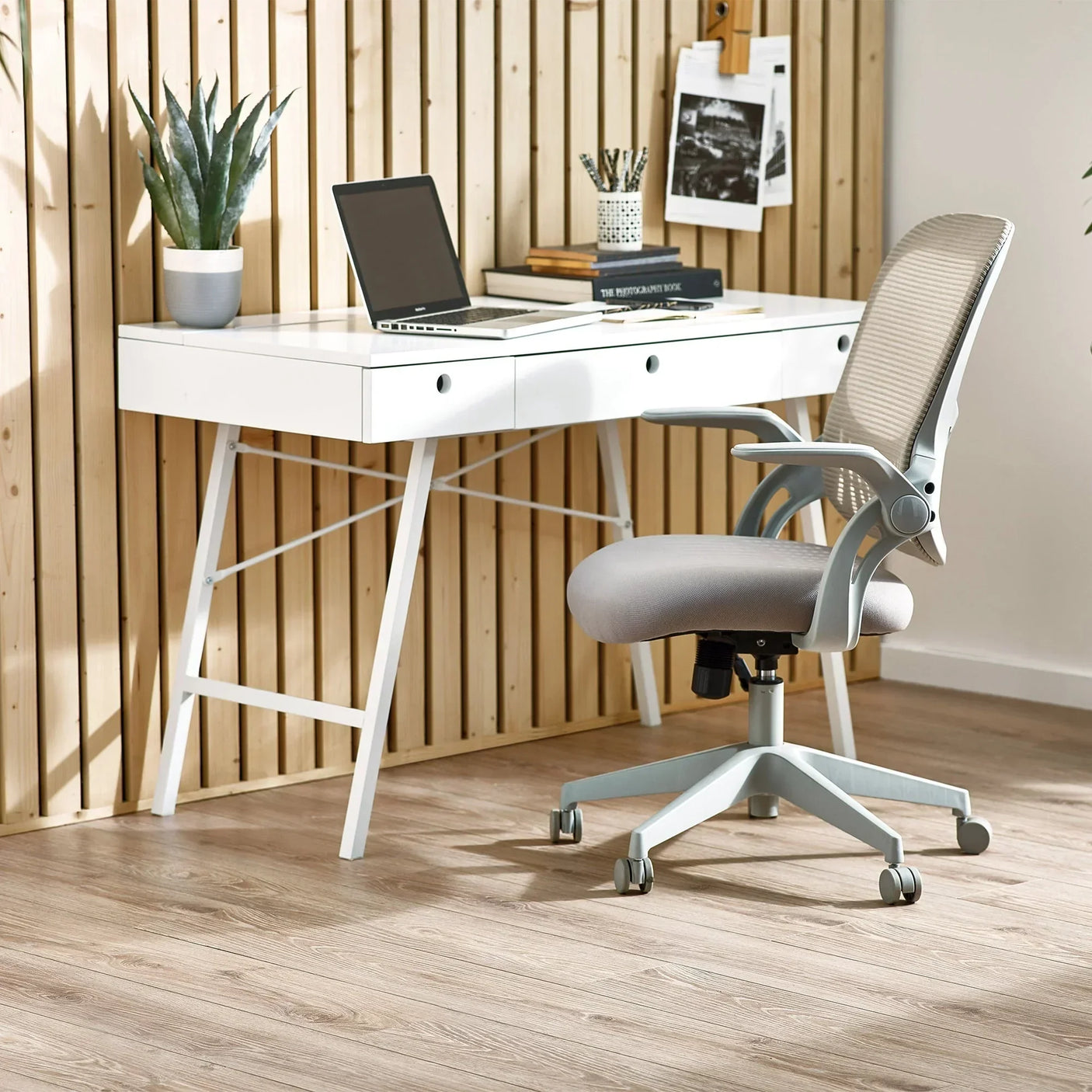 Light grey Juno office chair with mesh backrest next to white desk in modern workspace