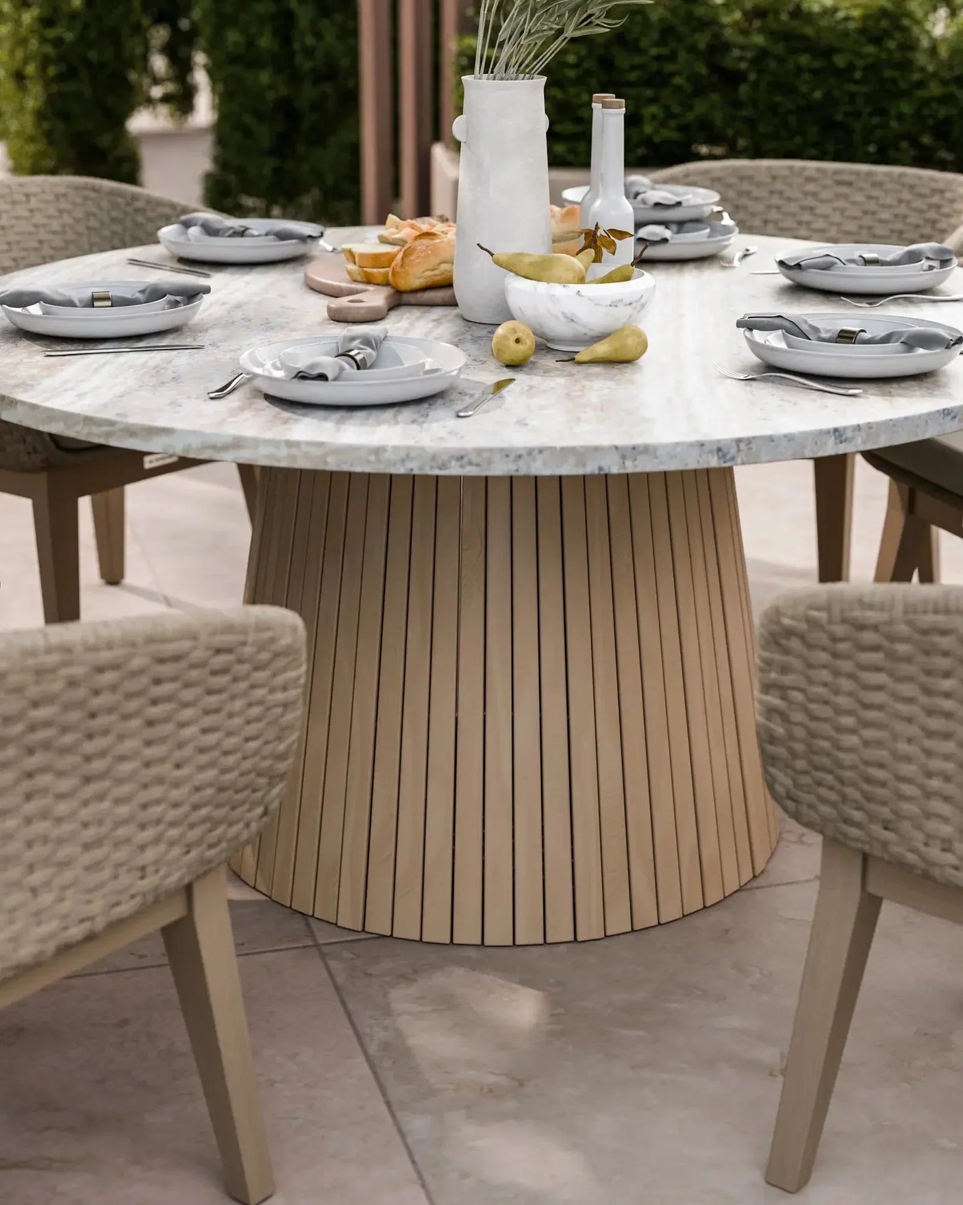 Round marble dining table with light wood base set for outdoor meal, woven chairs around