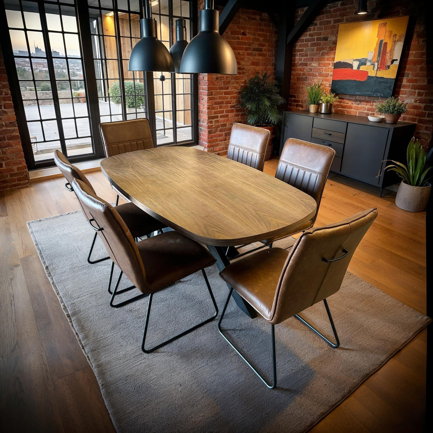 Walnut dining table with six cognac leather chairs in modern loft dining room
