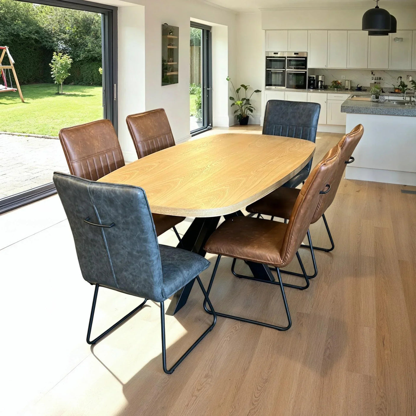 Oak dining table with grey and cognac chairs in modern kitchen dining area