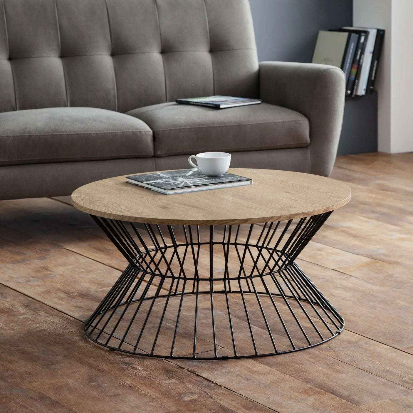 Light oak coffee table with round top and black wire base in modern living room