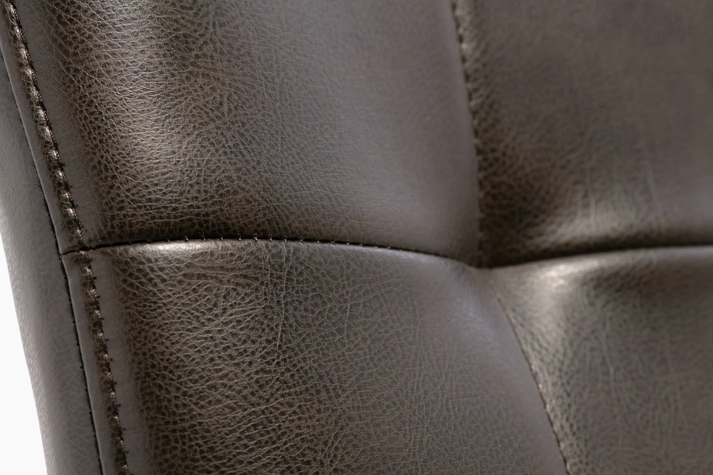 Close-up of brown faux leather dining chair stitching and textured upholstery