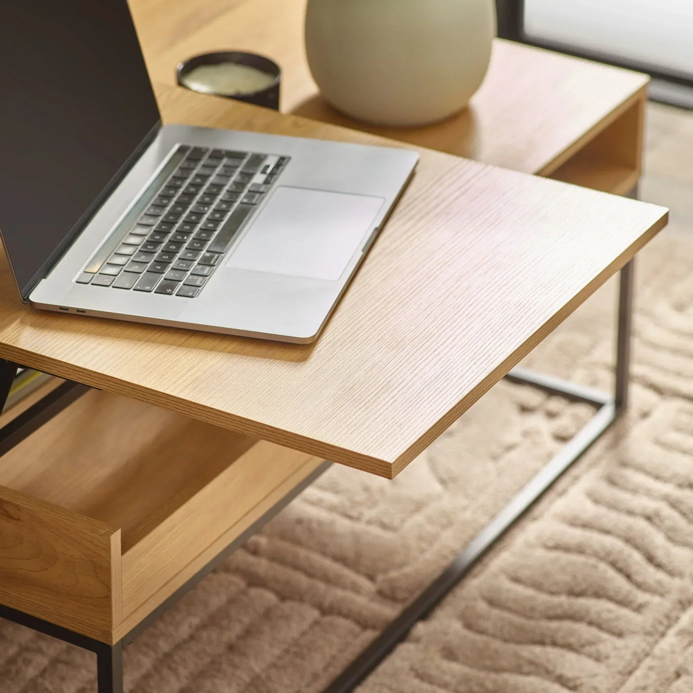 Light wood desk with metal frame featuring open drawer and laptop on beige patterned rug