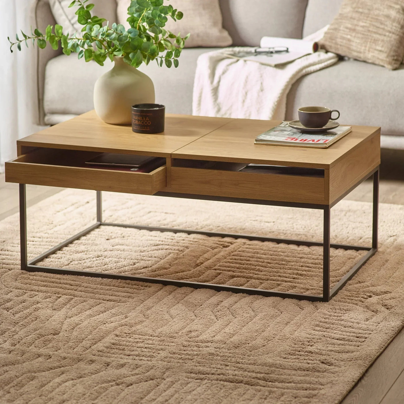Wood coffee table with metal frame, open drawer, cups and vase in modern living room