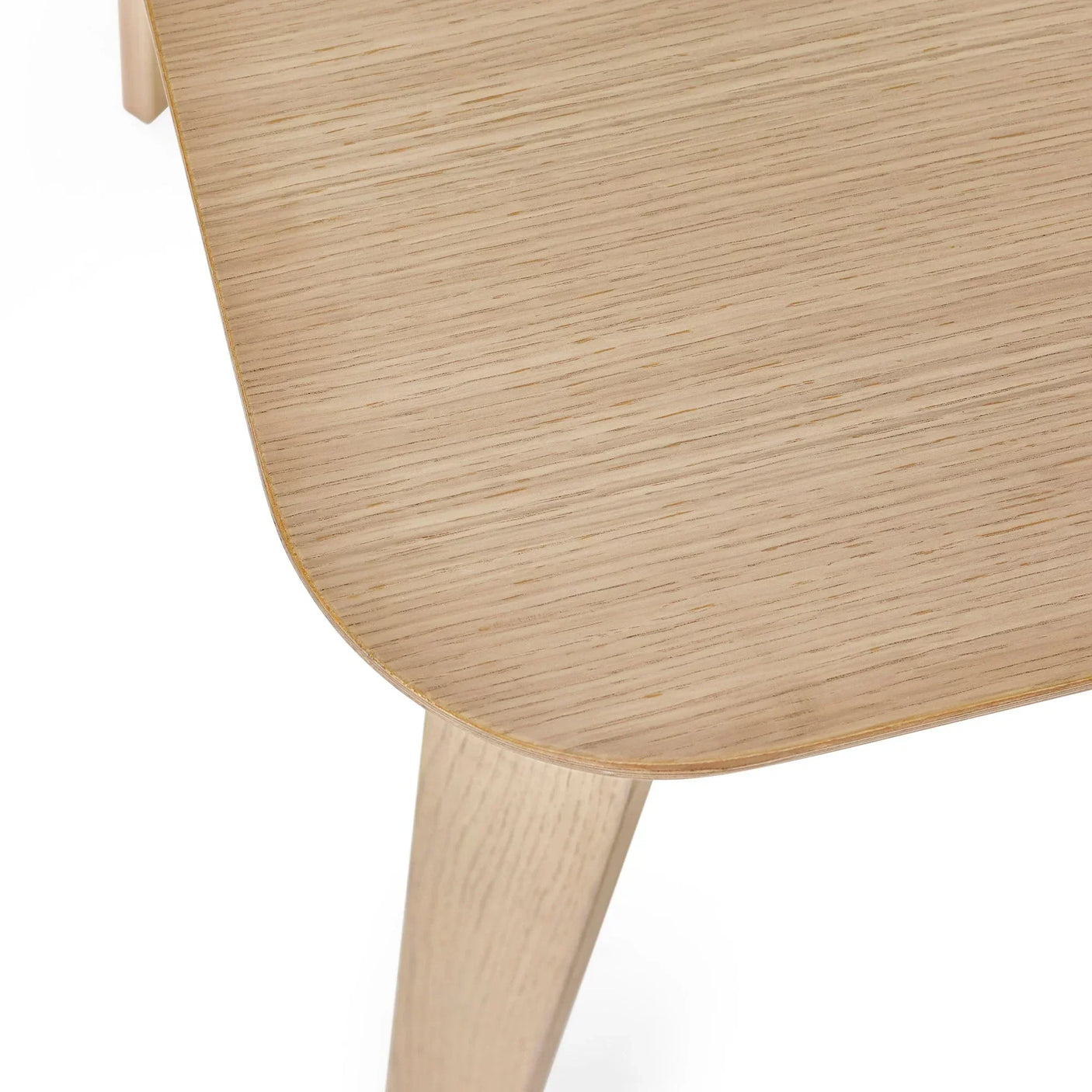 Closeup of light oak dining table corner with wood grain and angled leg