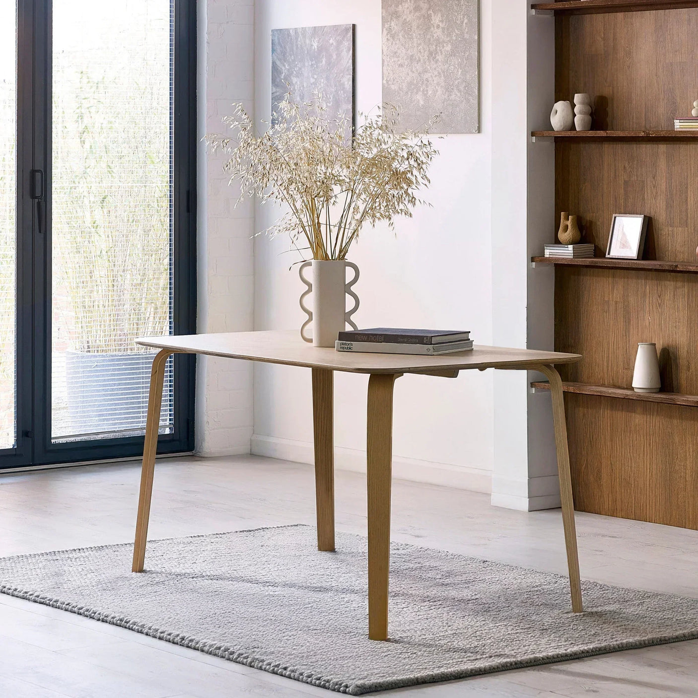 Rectangular wood dining table with curved legs on grey rug in modern dining room setting
