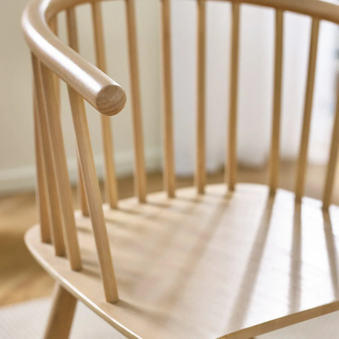 Natural wood dining chair with curved backrest and vertical spindle detailing