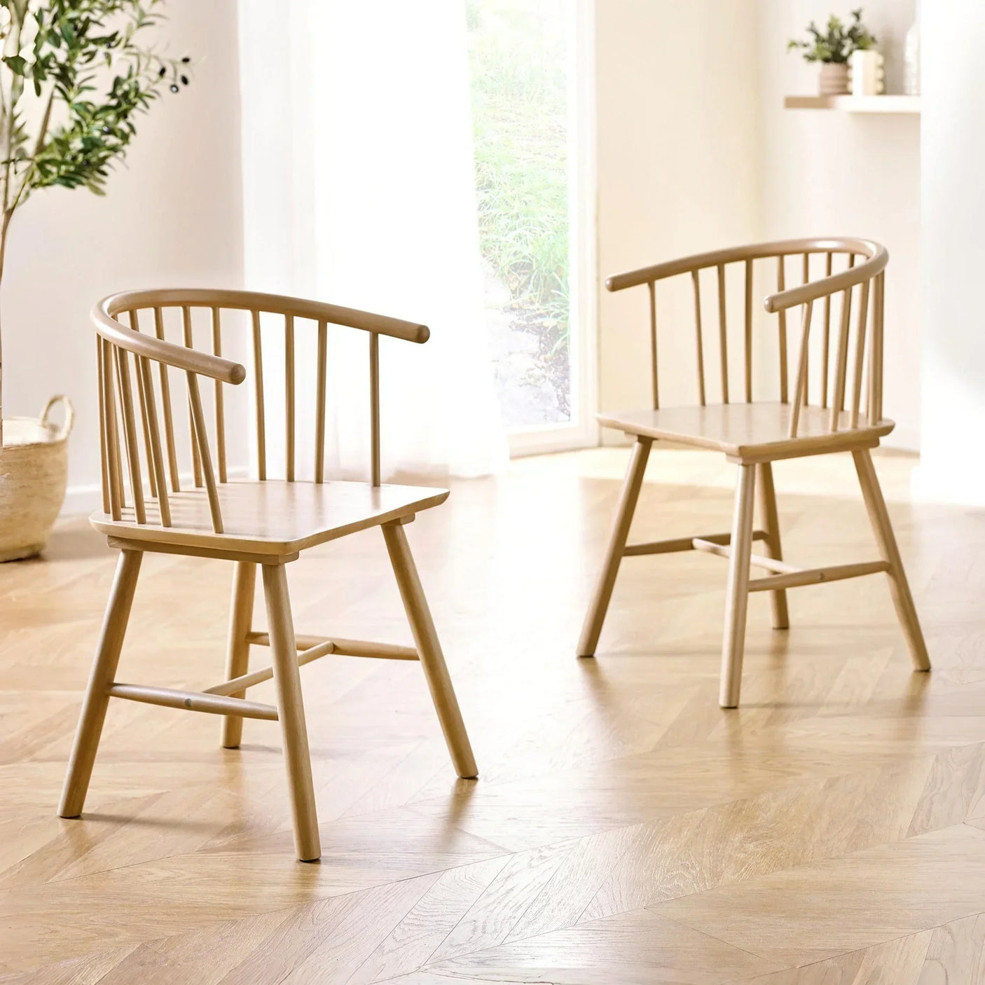 Pair of wooden dining chairs with spindle backs in a bright modern room on parquet flooring