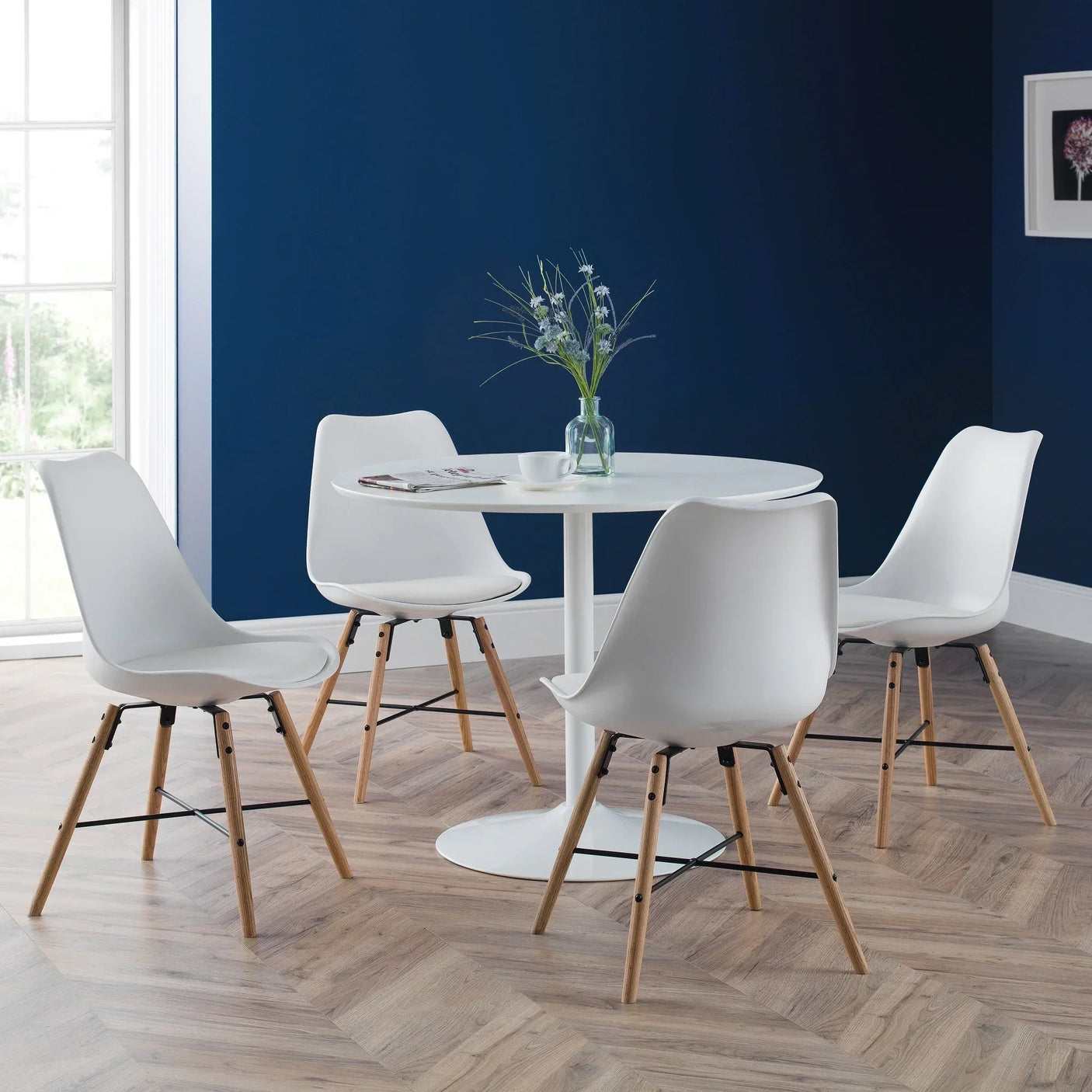 White dining chairs with wooden legs around round table in modern room with blue walls