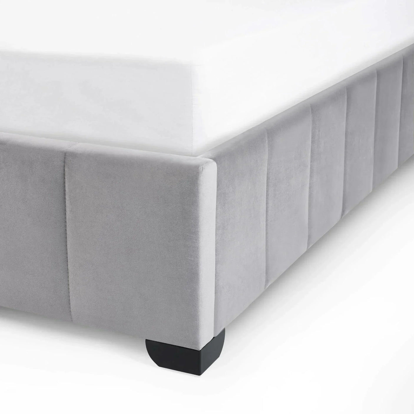 Close-up of grey velvet bed frame corner with panel detail and dark wood leg