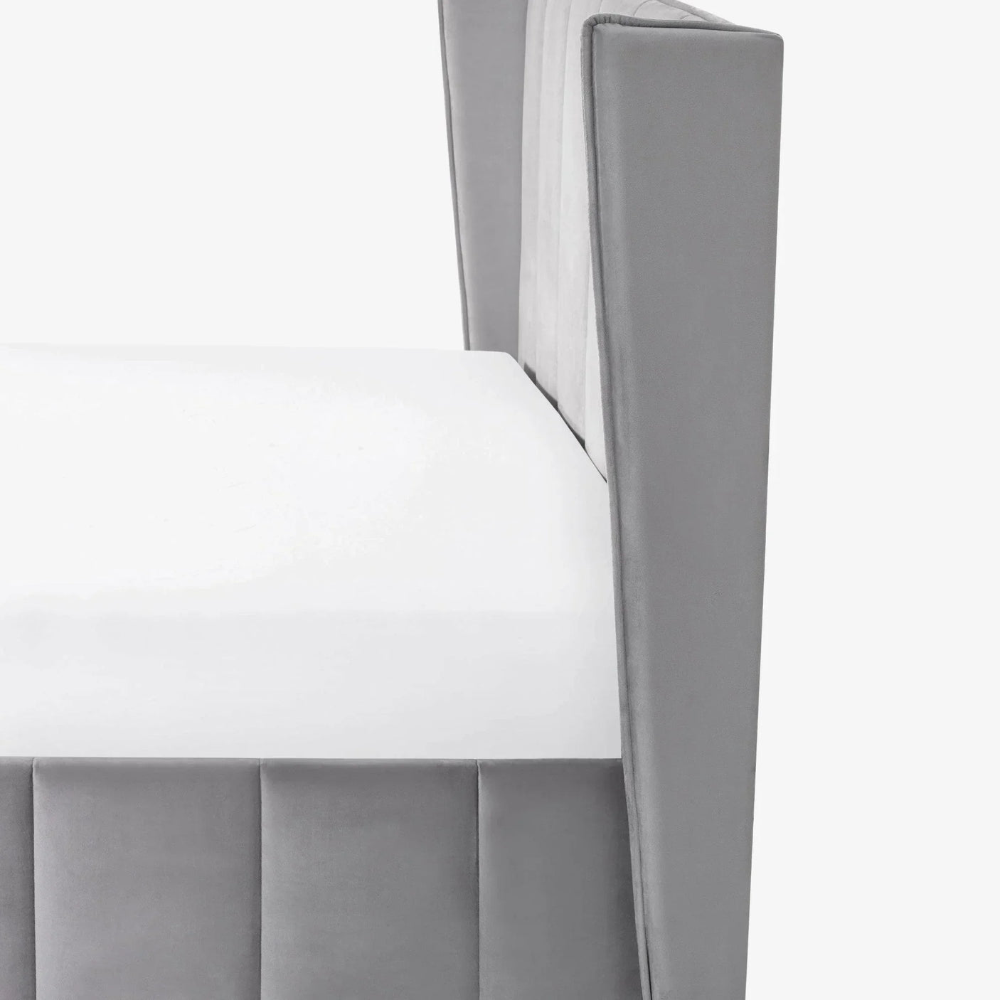 Closeup of grey velvet bed frame corner with white mattress and vertical panel detail