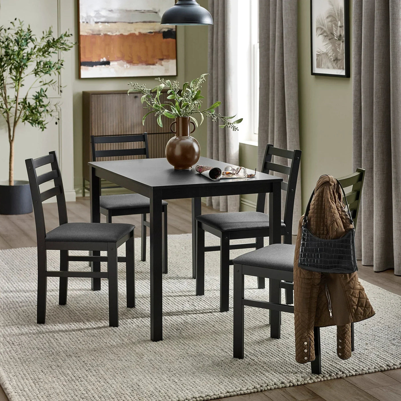 Black dining table set with four chairs on light rug in modern dining room
