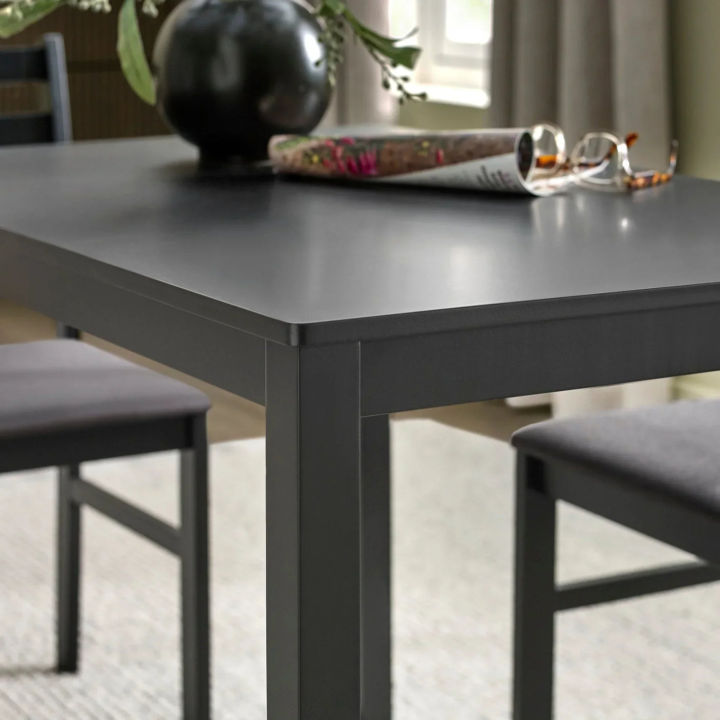 Black dining table with clean lines, paired with matching chairs in a modern room