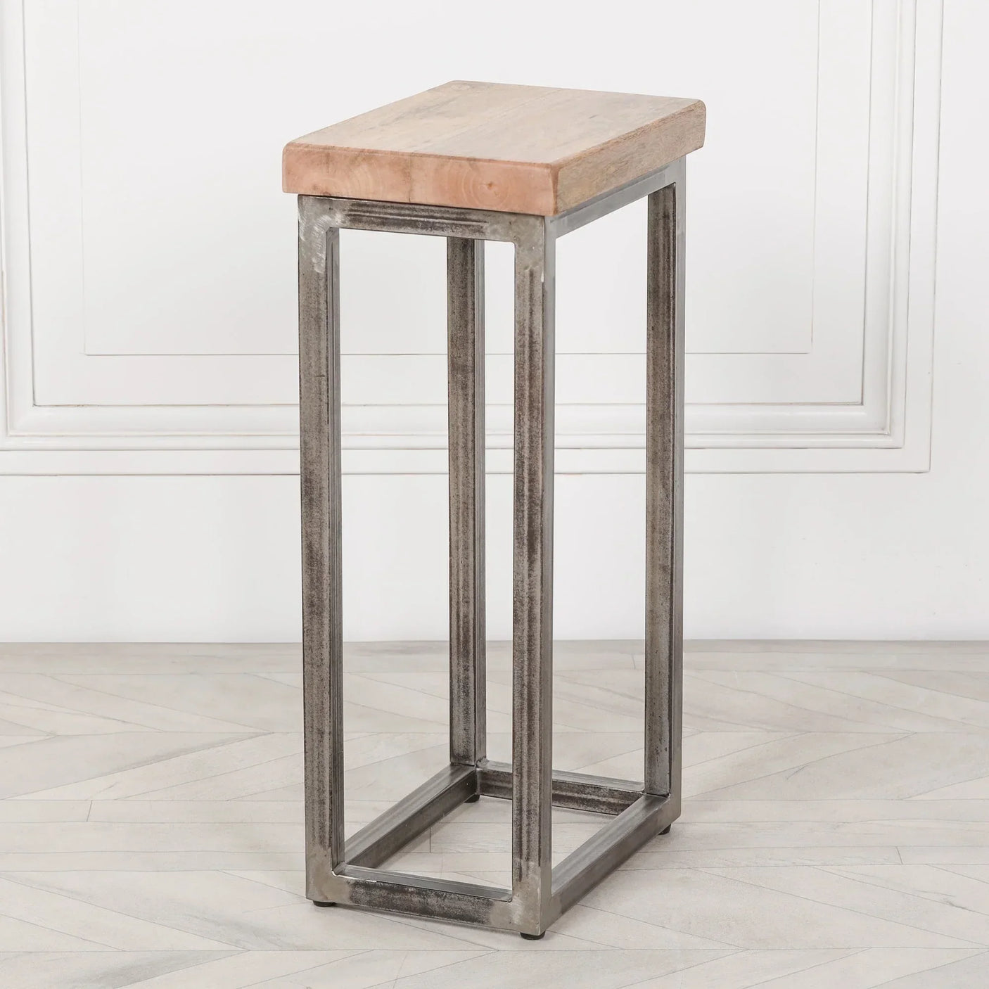 Industrial side table with light wood top and metal frame on herringbone floor