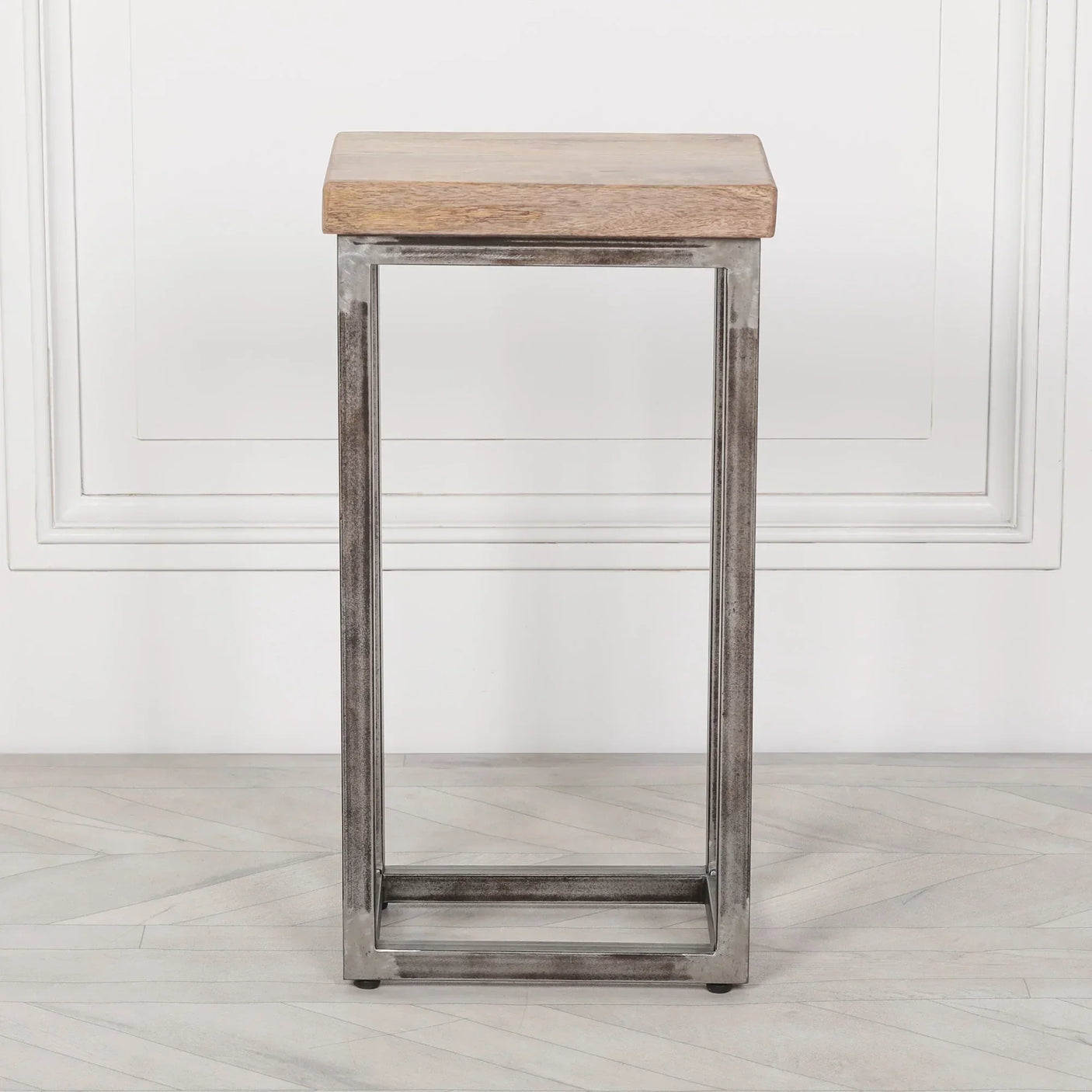 Industrial side table with metal frame and light wood top on herringbone flooring