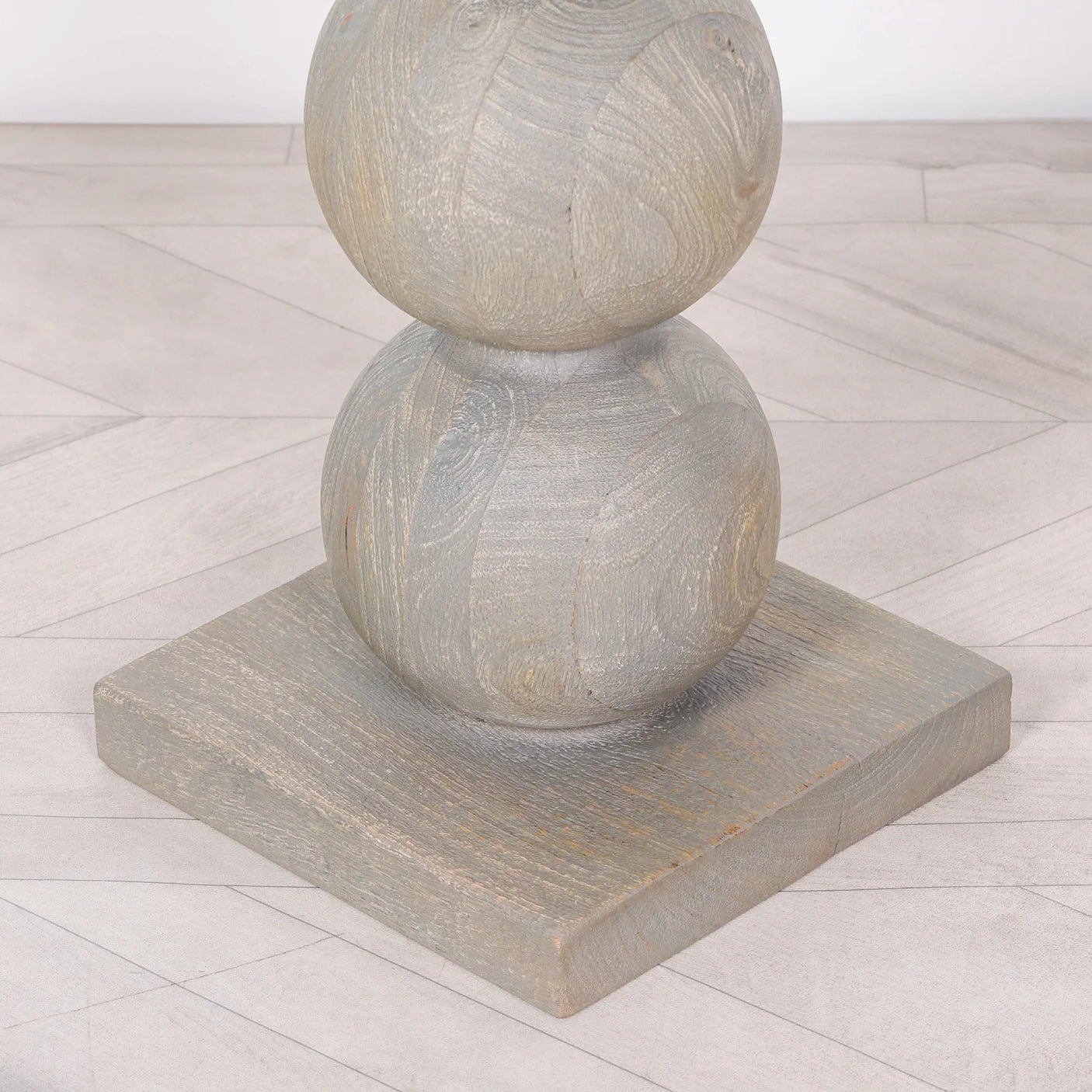 Grey wooden furniture leg with circular details and square base on light floor