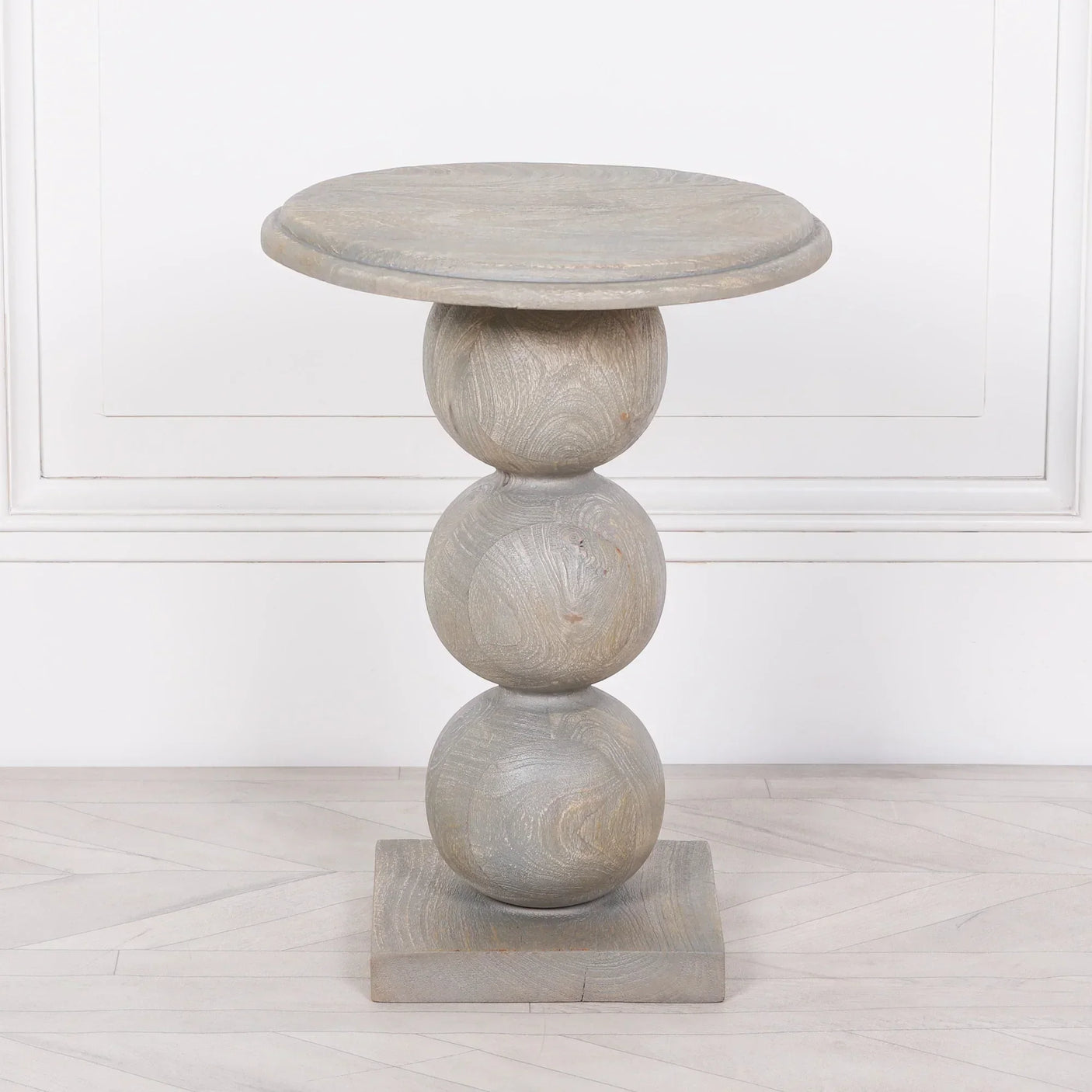 Light wood side table with round stacked base and circular top on parquet floor