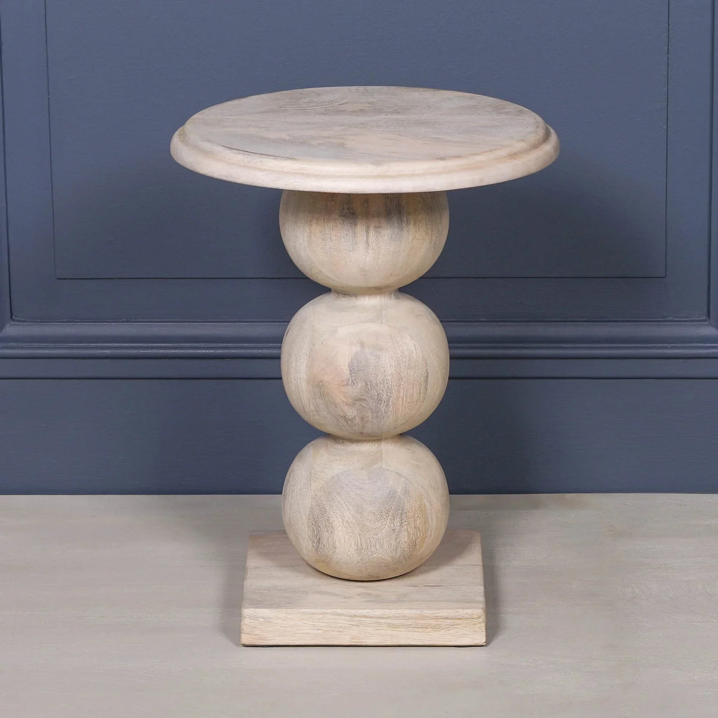 Light wood side table with round stacked base and square foot on grey background