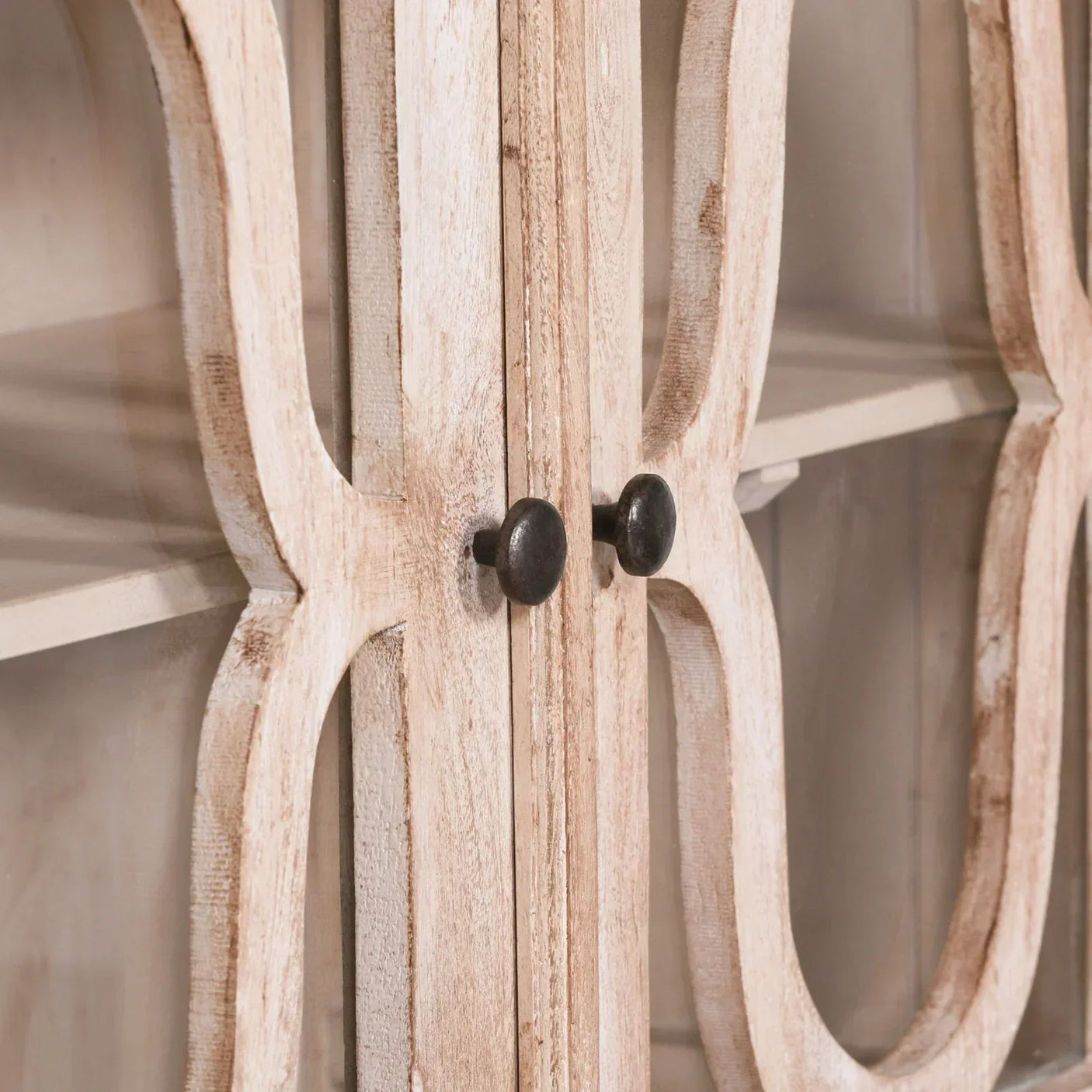 Closeup of wooden display cabinet doors with black knobs and glass panels