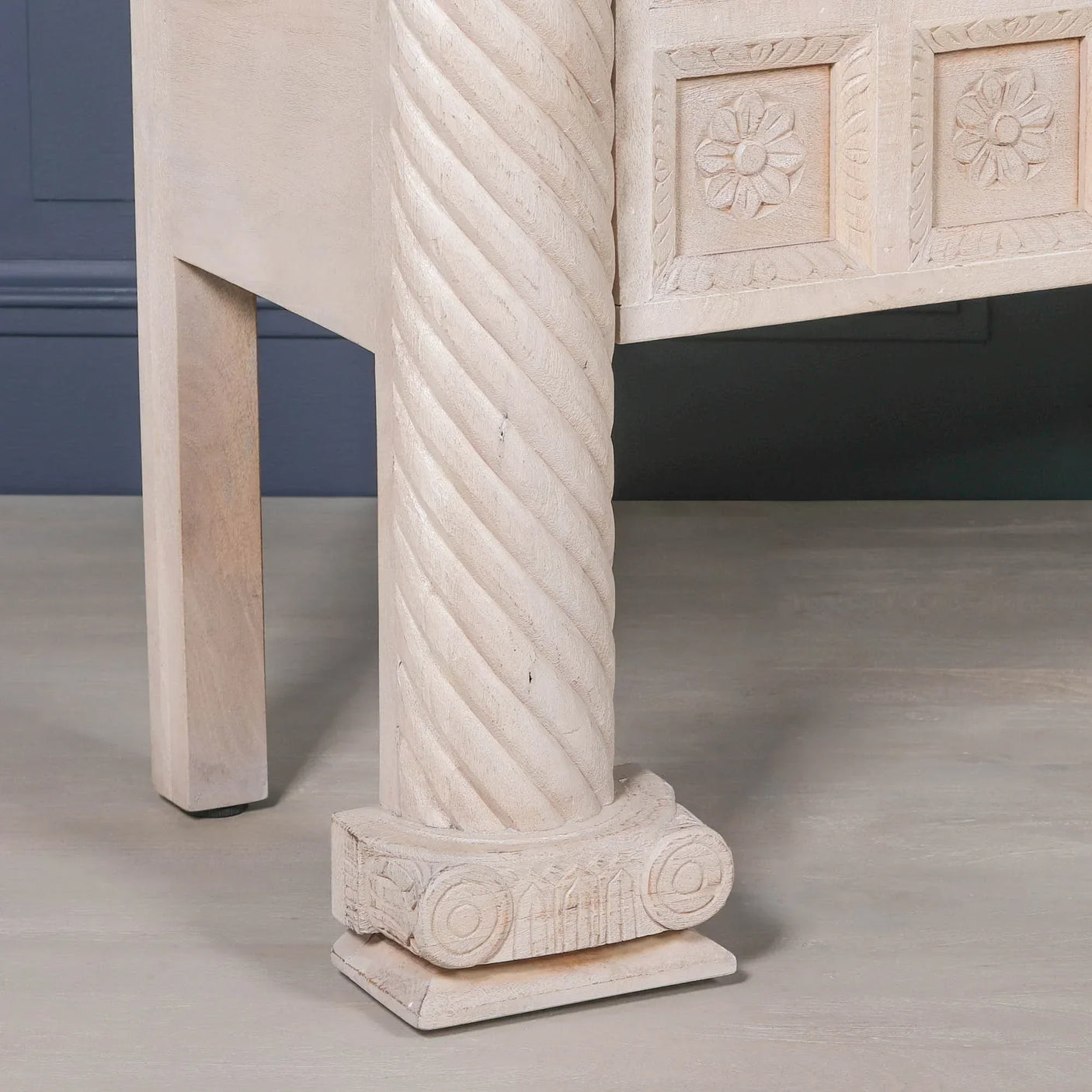 Carved wooden table leg with twisted column and floral detail in light finish