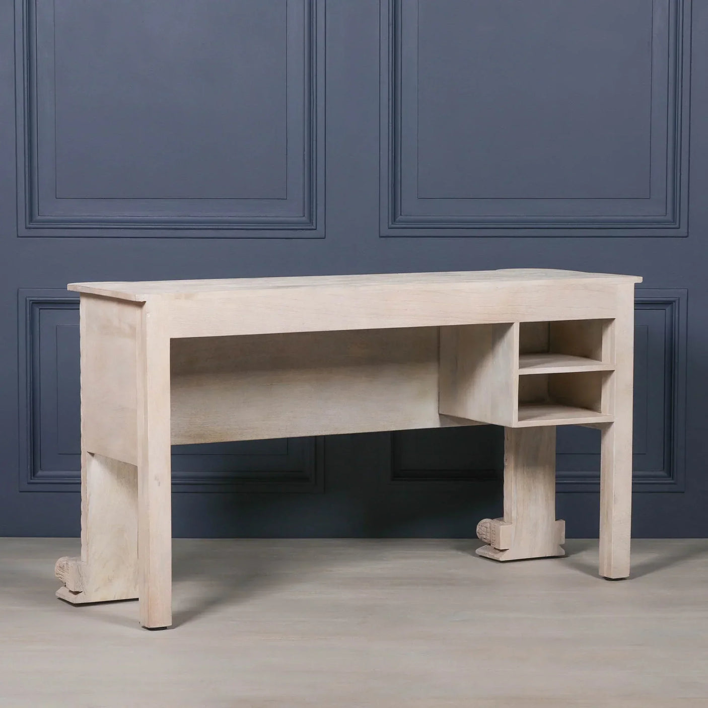 Light wood desk with open storage shelves against dark paneled wall