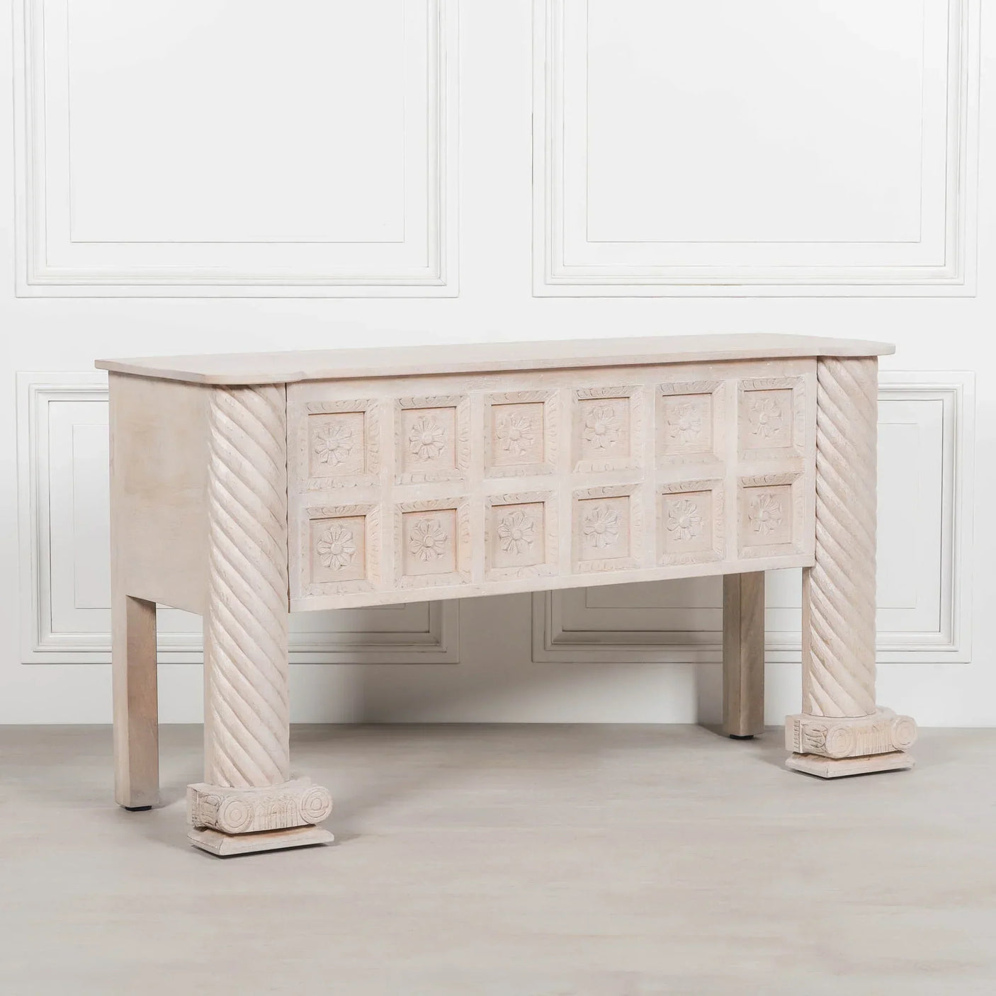 Carved wood console table with floral panel detailing and twisted column legs in light finish