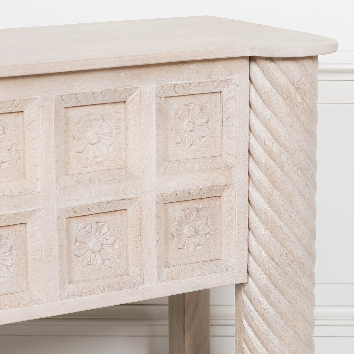 Carved wood console table corner with floral panel detail and twisted leg design