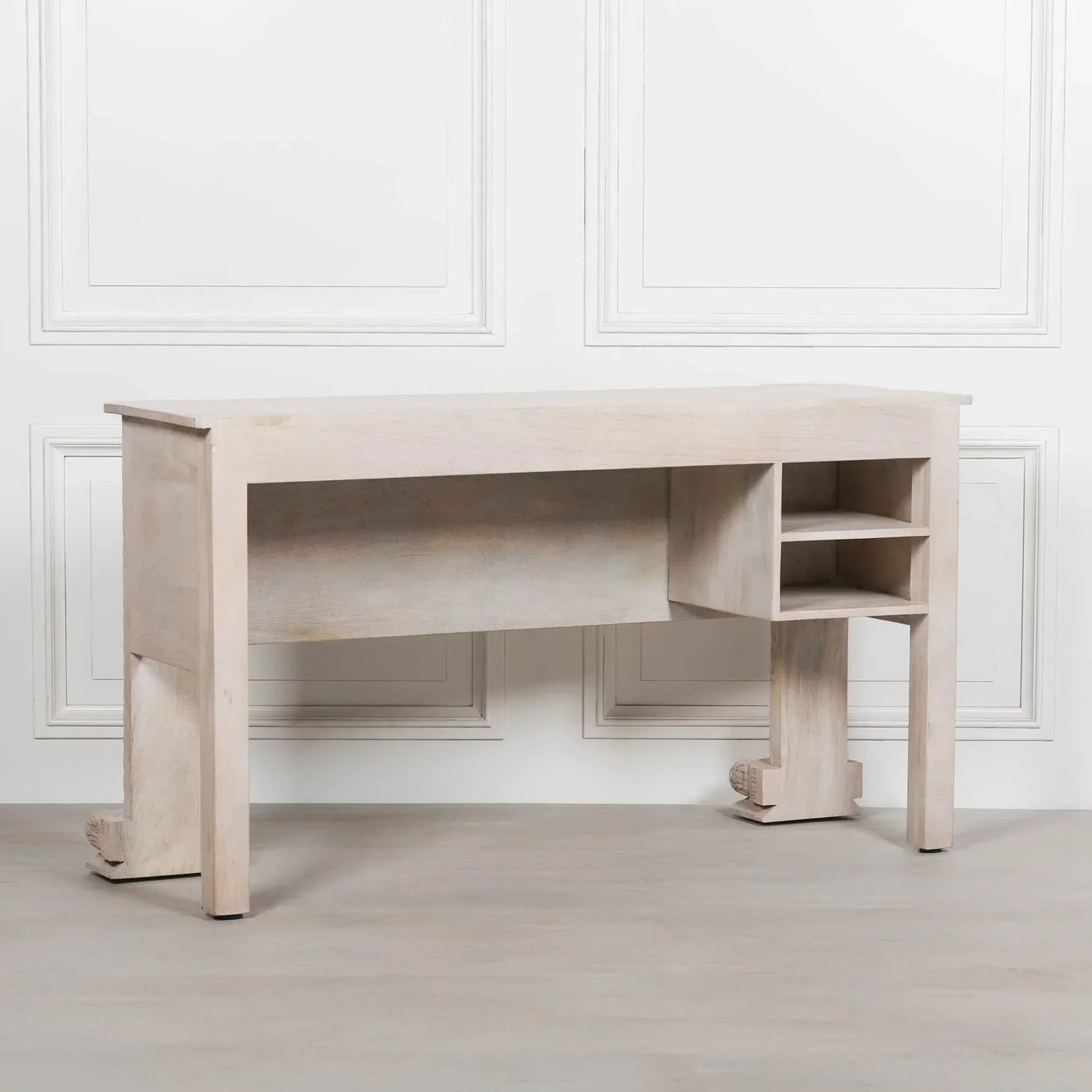 Light wood console table with open shelves against white paneled wall