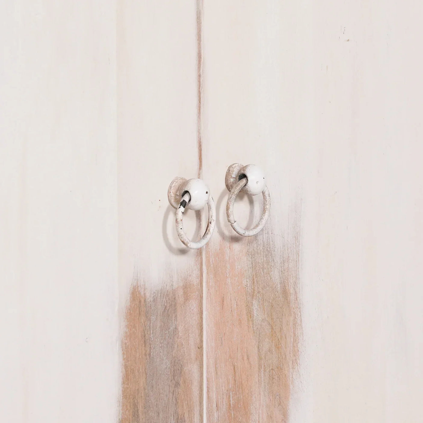 Distressed white wooden cabinet doors with rustic metal ring handles