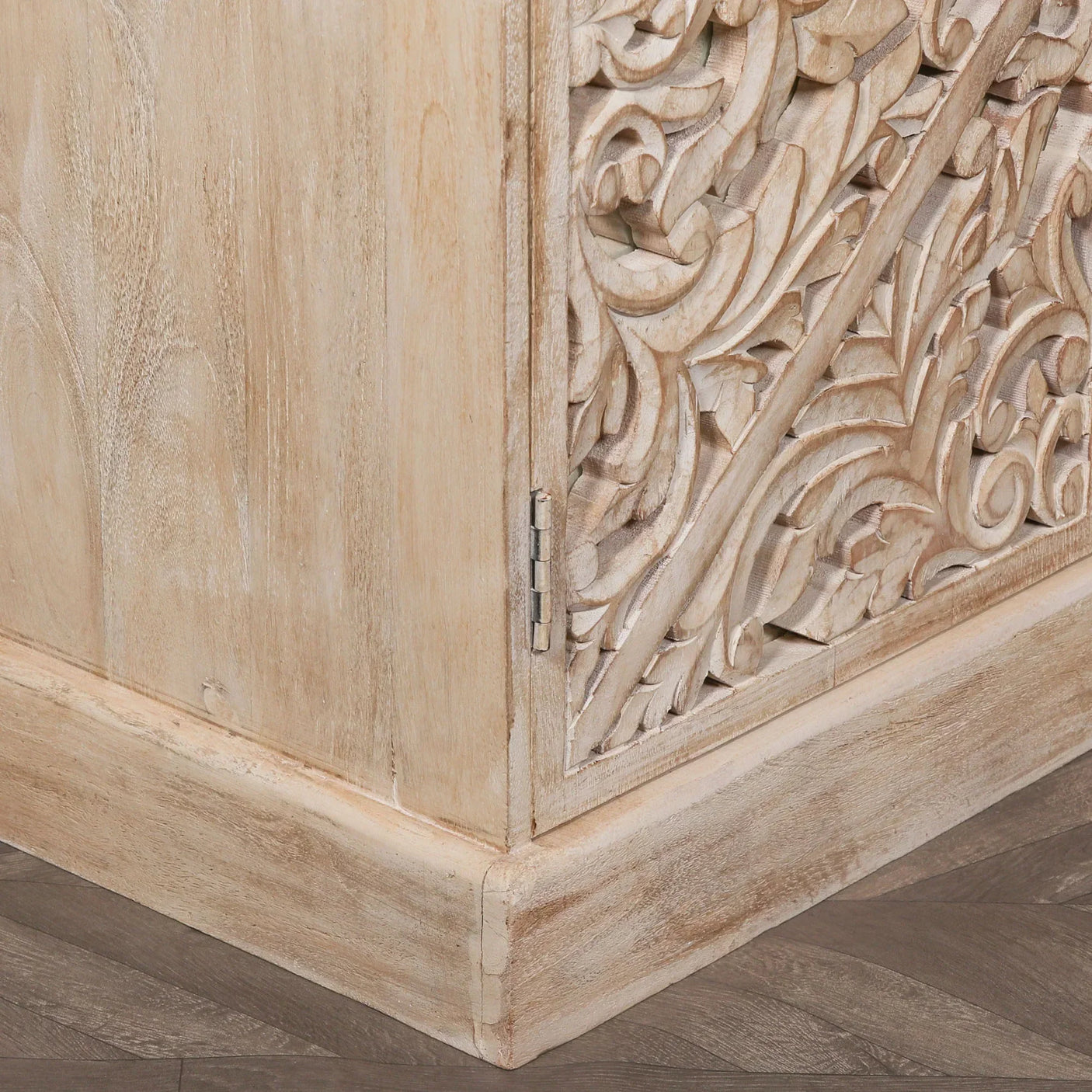 Corner of carved wooden cabinet with floral pattern and natural light wood finish