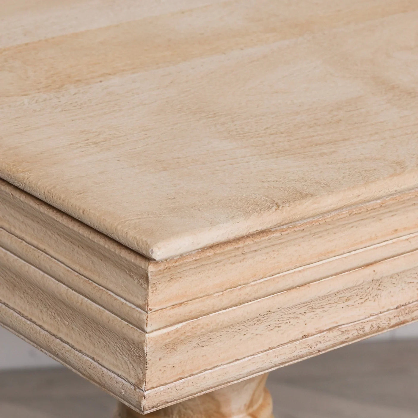 Close up of wooden dining table edge with natural light oak finish and carved detail