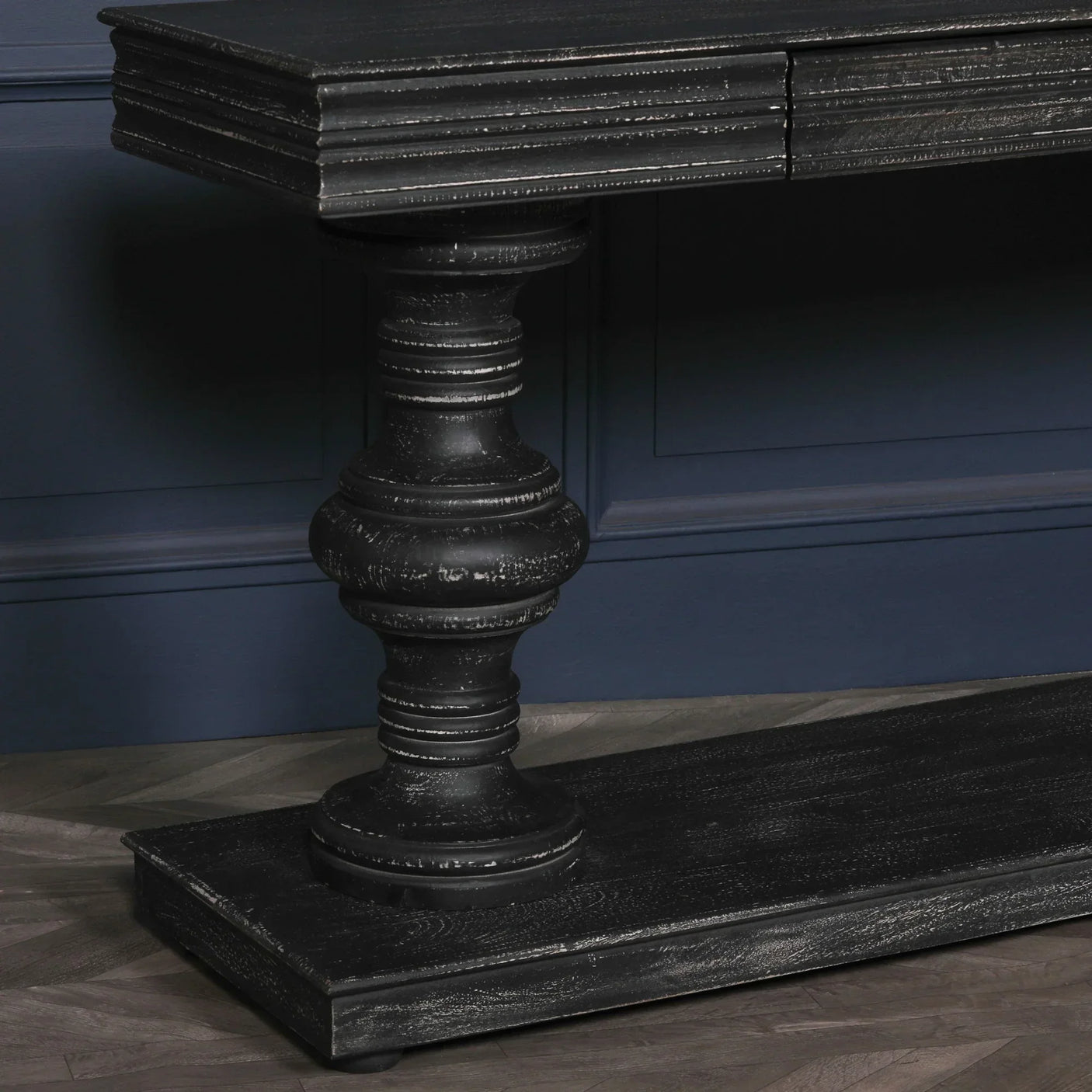 Black wood console table with turned leg and grooved detailing against blue wall