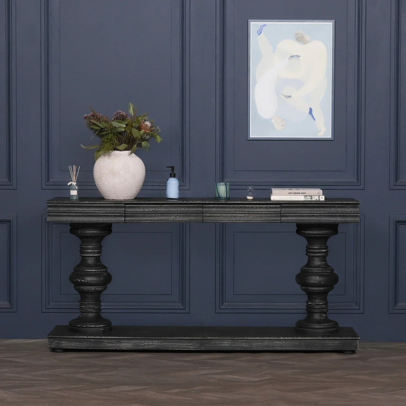 Black wooden console table with turned legs against navy wall, styled with vase and decor