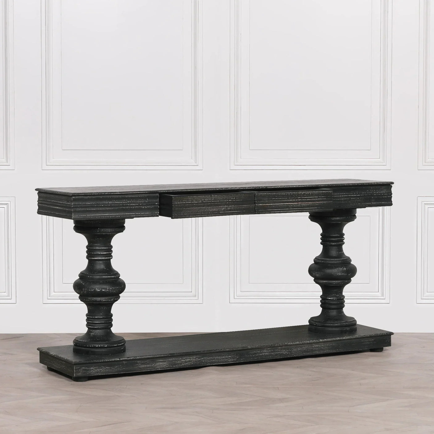 Black wooden console table with turned pedestal legs against a white paneled wall