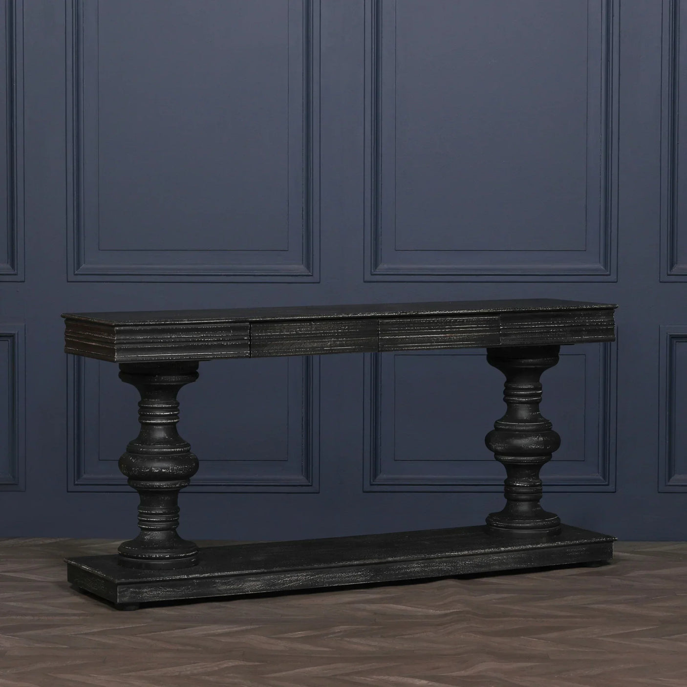 Black wooden console table with turned legs and rectangular top against blue panel wall