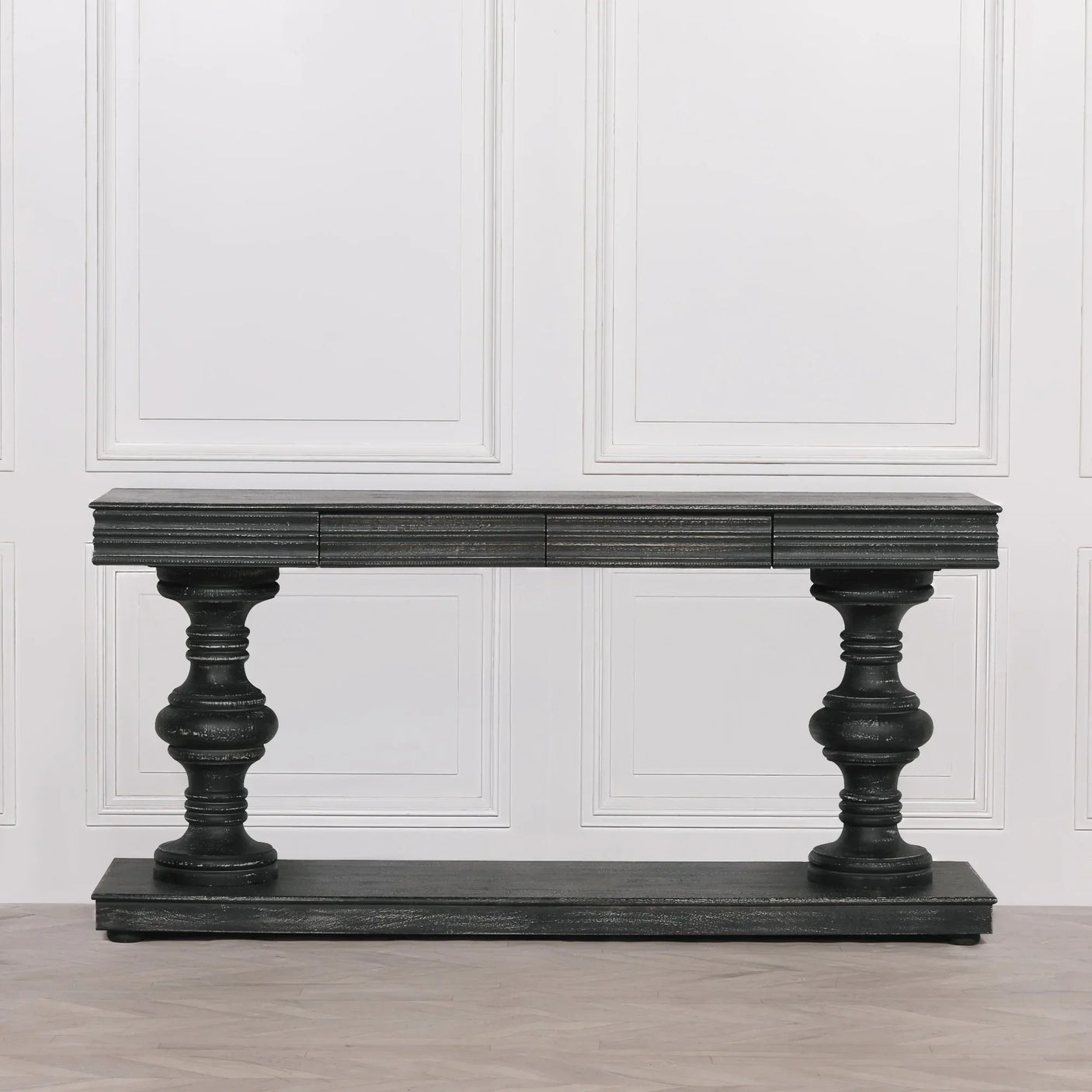Black wooden console table with turned legs and lower shelf against white panelled wall