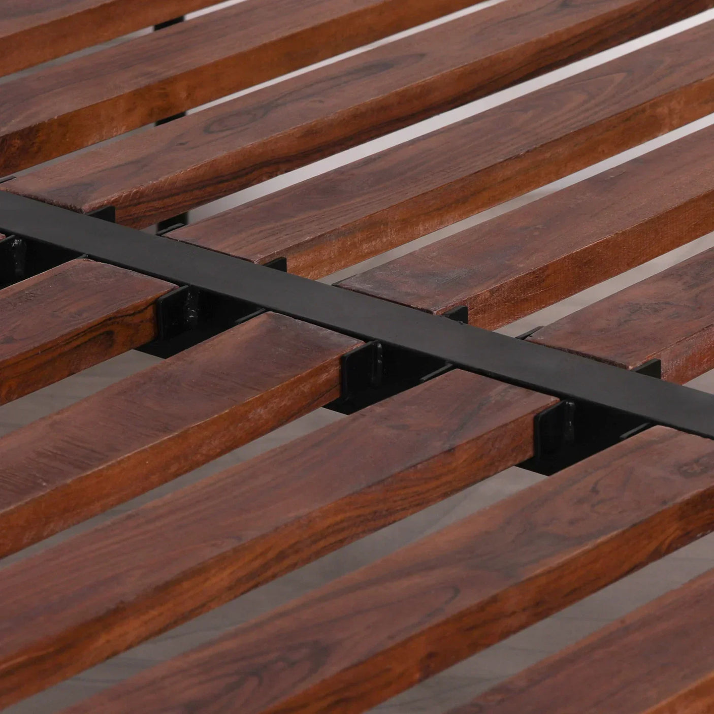 Wooden bed frame slats with metal support bar in close-up detail