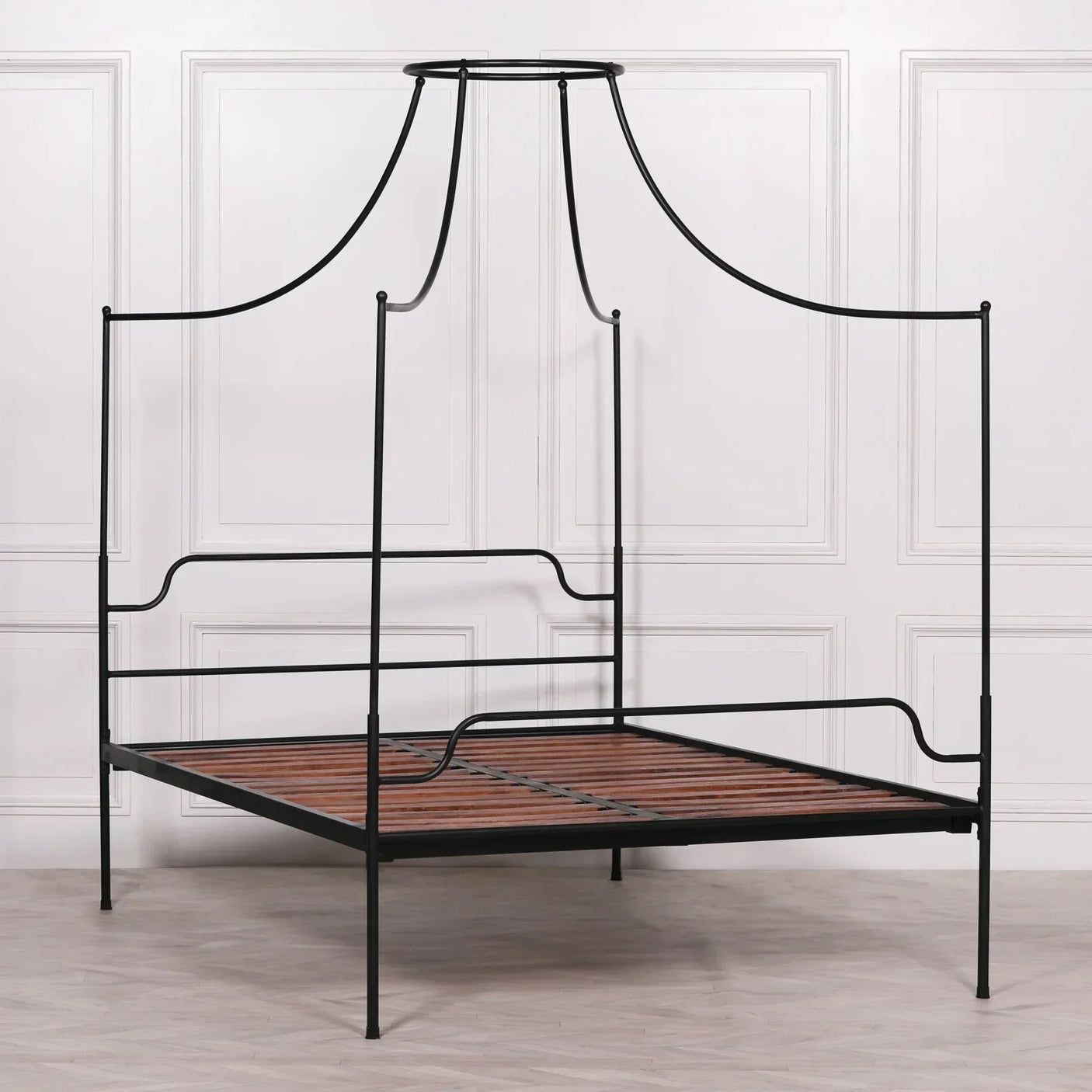 Black metal canopy bed frame with wooden slats against paneled white wall