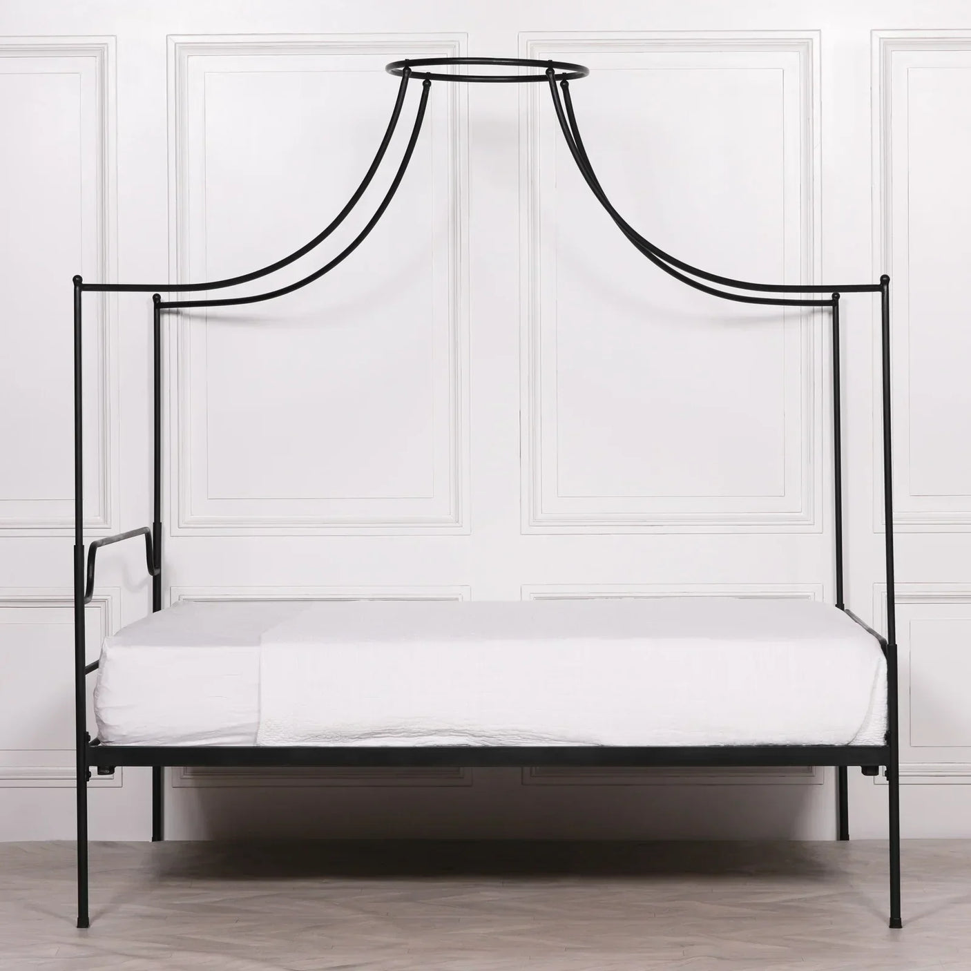 Black metal canopy bed frame with minimalist design and white bedding in modern room