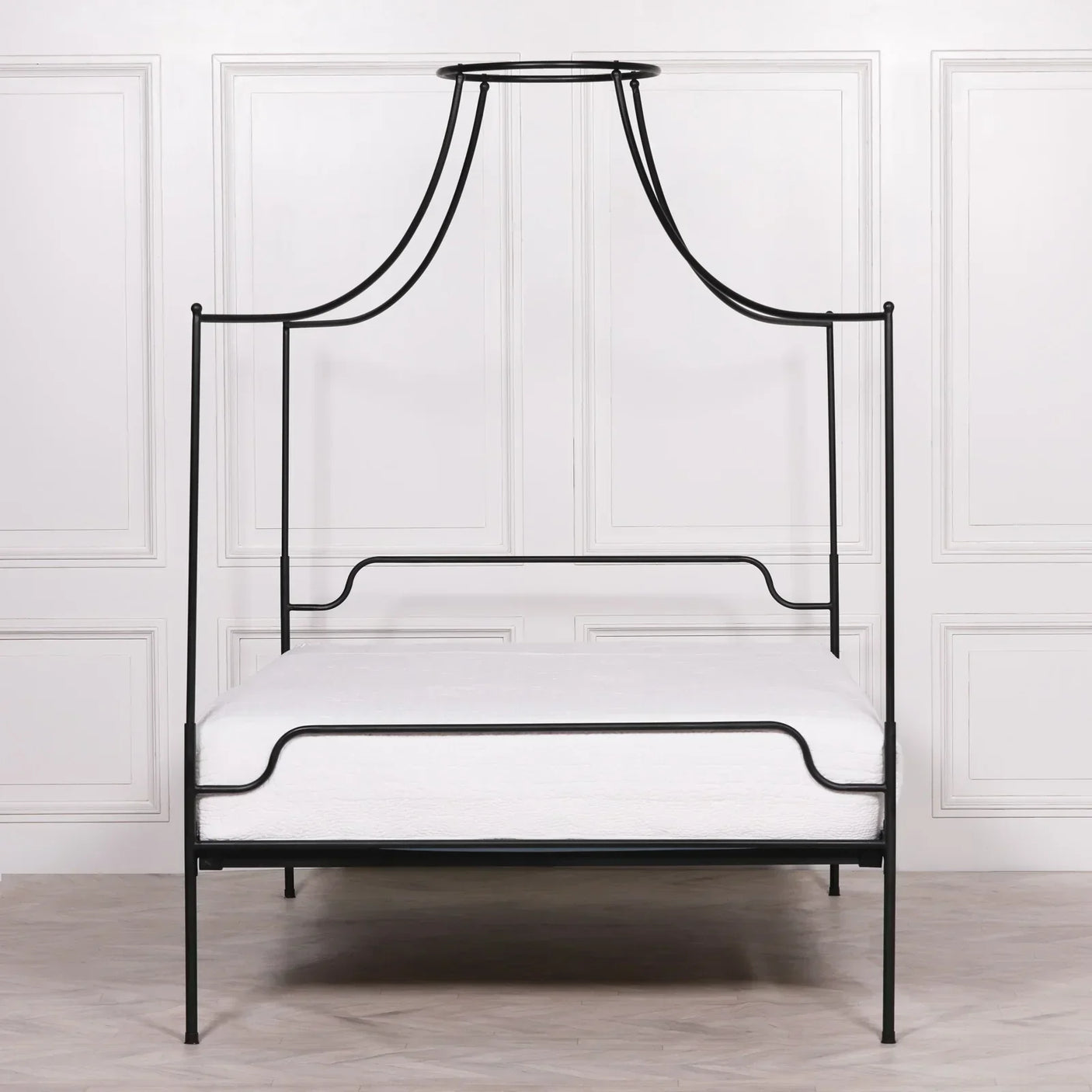 Black metal canopy bed frame with minimalist design against white paneled wall