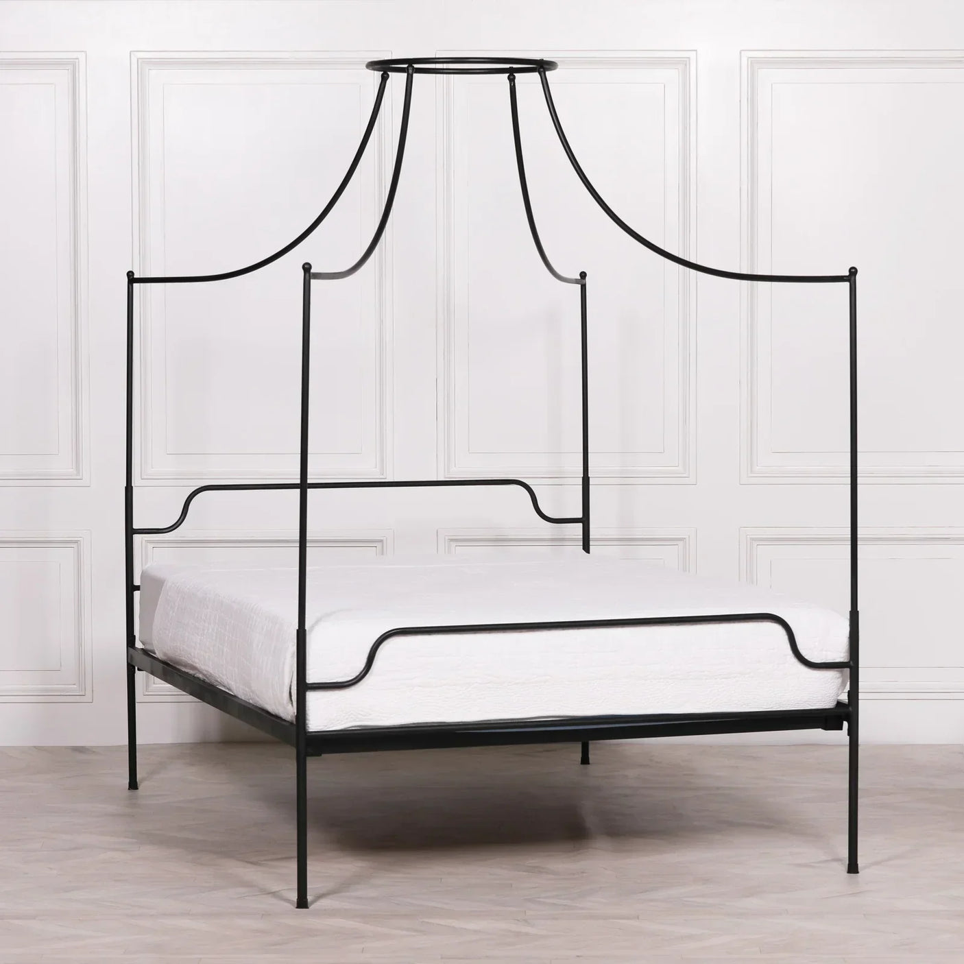 Black metal four poster bed frame with canopy in a minimalist bedroom setting
